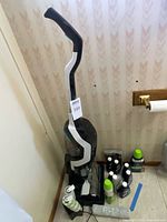 Vacuum standing on base with accessories and cleaning bottles