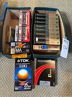 Overview of lot showing trays with blank audio cassettes, Betamax tapes, VHS tape and boxed rewinder