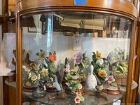 Showcase view of multiple hummingbird figurines, bell and pewter piece