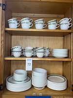 Shelved dinnerware set showing cups, bowls and plates