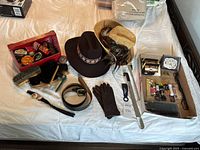 Overview of all items on bed including hats, shoe care kit, belts, buckle, gloves, shoelaces