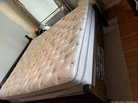 Full view of assembled bedframe with mattress on top showing headboard posts and carved footboard