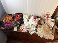 Overview of lot showing Mola, piles of handkerchiefs, crochet pieces