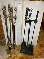Both brass and black fireplace tool sets side by side