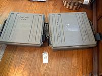 Two closed grey first aid cases on wood floor