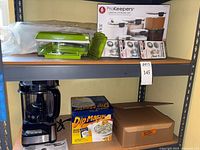 Shelf view showing all items including food processor, ProKeepers box, cord wrappers, DipMasters box, bamboo steamer box and green chopper