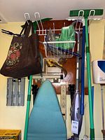 Wall-mounted cleaning tools including EasyEdge sweeper, Swiffer WetJet, ironing board, wire rack, power strips and accessories