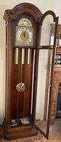 Full view of grandfather clock with door open showing weights and pendulum