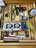 Drawer section showing packaged dial thermometers, loose dial thermometer, glass probe thermometers and assorted small kitchen tools