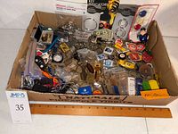overview of box with assorted keychains and ruler for scale