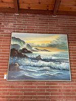 Full view of framed ocean landscape painting on brick wall
