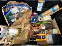 Assortment of brushes, tapes, paper rolls, roller frame and covers inside bin