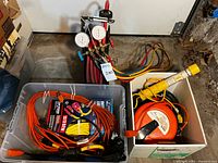 Overall view of lot: manifold with hoses, bin of extension cords, box with cord reel and work light