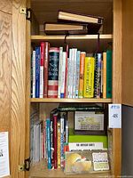 Two-shelf oak cabinet holding cookbooks and reference items