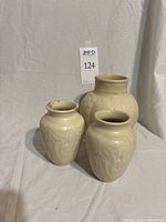 Front view of three cream Rookwood vases