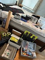 Overview of lot on bed and floor, showing cases, targets, ear muffs, glasses, toolbox, crate