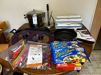 All items on table: stock pot, griddle, silicone lids, fry pan, WrapMasters, clips, Ziploc bags