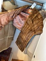 Fur wrap open showing peach satin lining and shearling jacket hanging nearby