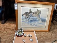 Framed wolf artwork and figurines in front