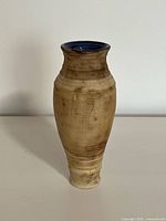 Full view of handmade earthenware vase showing tall, narrow shape and matte beige exterior with subtle texture.
