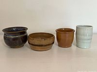 Four glazed pottery pieces in varying shapes and colors side by side.