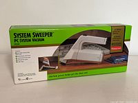 Front angled view of the boxed System Sweeper vacuum showing product image, brand, and power cord length details.