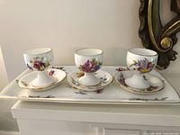 Front view of three egg cups on saucers displayed on tray