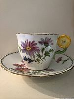 Teacup on saucer showing floral design and flower handle