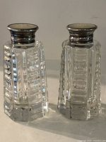 Front view of both shakers showing faceted cut glass bodies and sterling caps