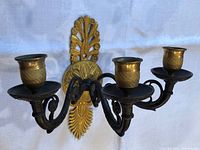 Front view showing three arms, candle cups and decorative backplate