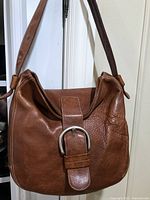 Front view of tan leather shoulder bag hanging