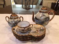 group view of complete Kutani tea set: teapot, sugar bowl, teacup, stack of six saucers