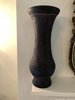 Full front view of dark acid-etched glass vase on shelf