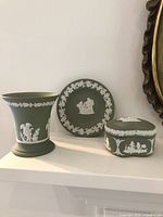 Three Wedgwood green jasperware pieces on shelf