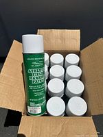 Box containing 12 unopened white spray paint cans labeled 'Athletic Specialty Inc Athletic Field Marking Paint'. One can is shown standing upright outside the box.