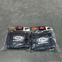 Front view of two black Easton equipment bags side by side in original clear plastic packaging showing Easton logo and product label.