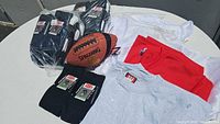 Football, multiple t-shirts, and socks displayed on round table.