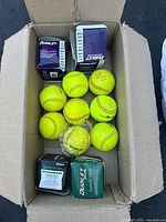 Photo of a box containing 12 Dudley softballs and their original packaging boxes, showing bright yellow balls with red stitching in new condition.