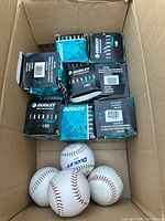 Box containing 12 Dudley brand softball boxes with 3 softballs visible outside the boxes inside the larger box.