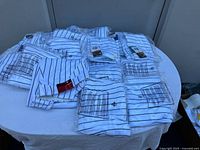 Photo showing all 20 pairs of men's Wilson baseball pants, folded and stacked on a table, with visible brand tags and size charts.