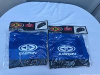 Photo showing two bright blue Easton branded tote bags in original sealed packaging.