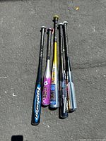 Top-down view of five aluminum baseball bats arranged together, showing various colors and branding.
