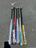 Photo of 5 aluminum baseball bats standing upright showing side view with varying colors and brand decals including Dudley, Spalding, Easton, Miken, Havoc