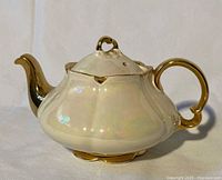 Side view showing pearlescent body, gold handle and spout