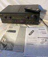 Front view of Technics SA-AX730 receiver, remote on top, manuals in foreground