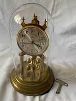 Front view showing complete clock under glass dome with key