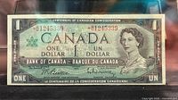 Front of the 1967 Canada one dollar replacement note showing Queen Elizabeth II portrait, serial number with asterisk, and dual English-French text.