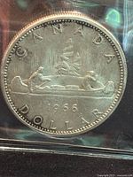 Obverse side of the 1966 Canada Voyageur silver dollar coin, showing two figures paddling a canoe with year and inscriptions.