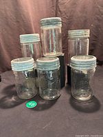 Photo showing all six vintage clear glass canning jars with metal screw rings and glass lids.