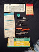 Photo of vintage drafting and measuring tools spread on black cloth including measurement converter, metric conversion guide, compasses, scissors, knives, and drafting calculation aids